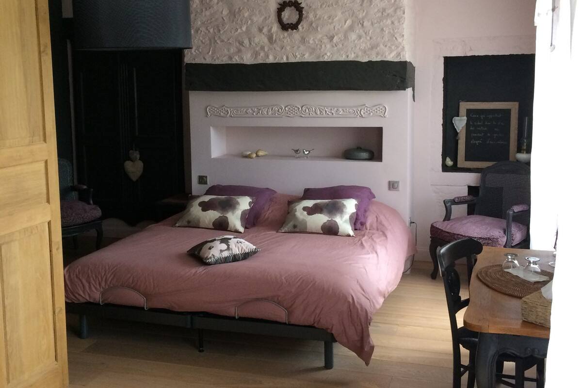 Un dormitorio con cama, cómoda, silla, mesita y estante en la pared.