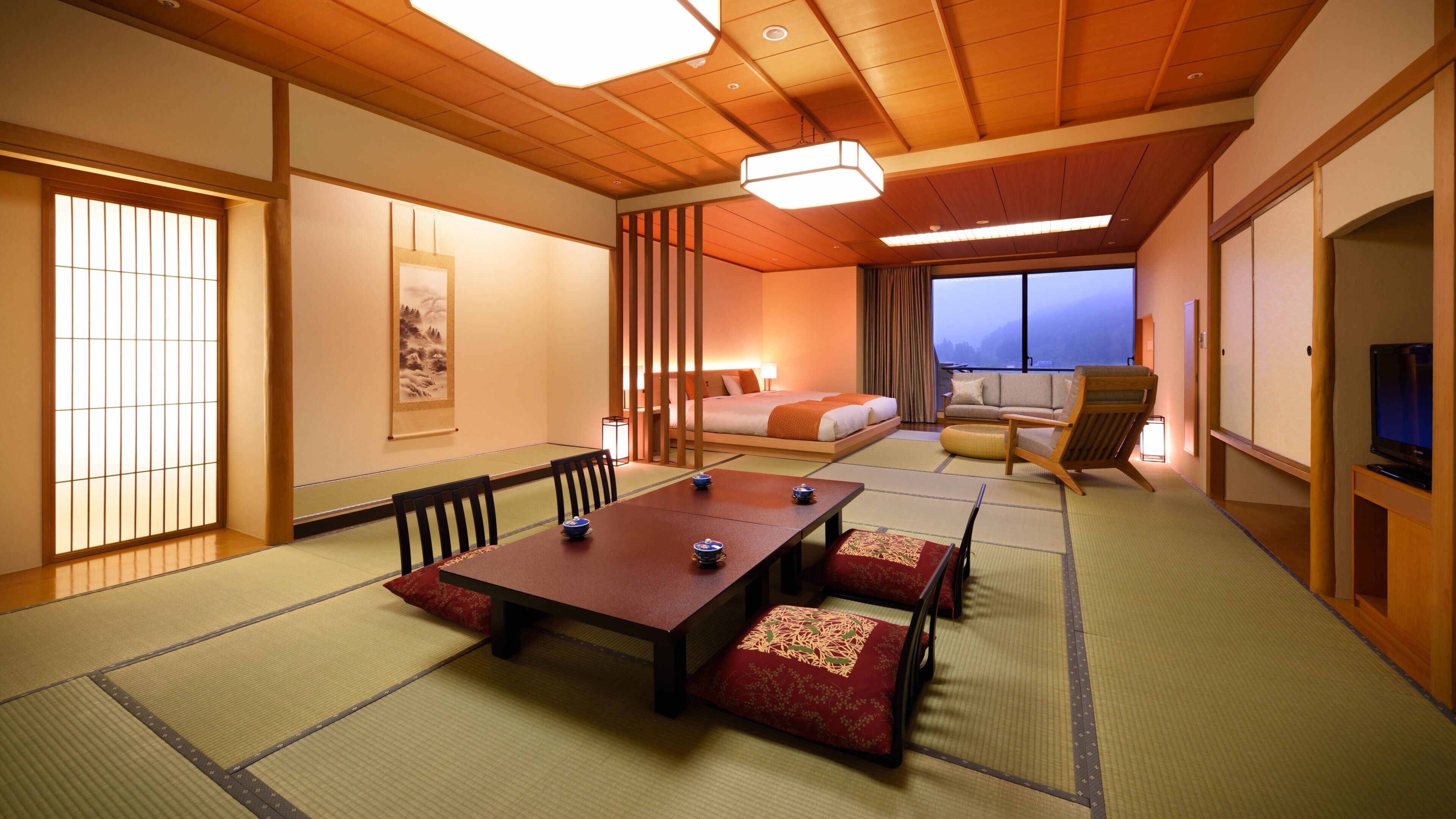 Ein traditioneller japanischer Raum mit Tatami-Böden, einem niedrigen Tisch, einer Couch, einem Bett und einem Fernseher.