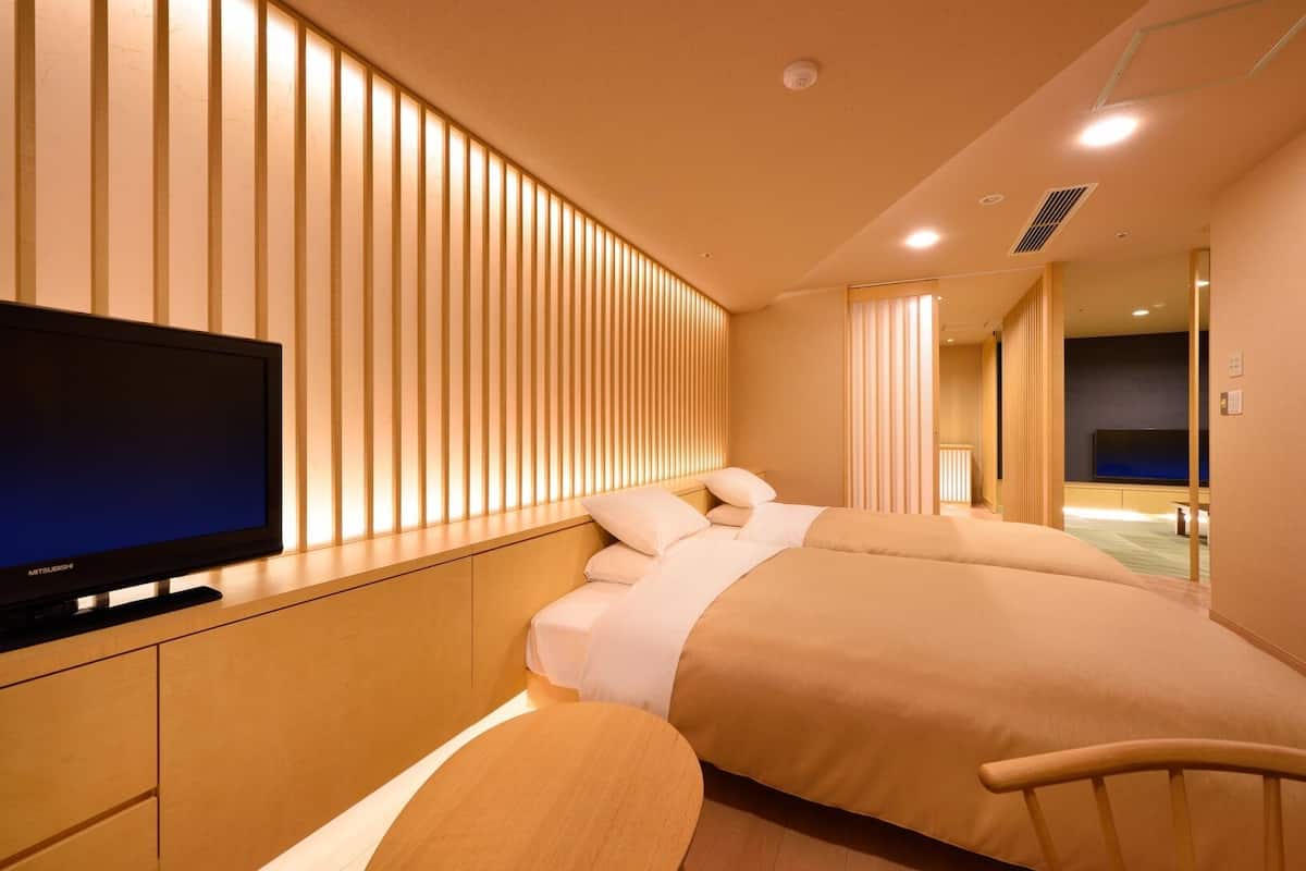 Ein Hotelzimmer mit einem Bett, einem Fernseher und einem hölzernen Kopfteil.