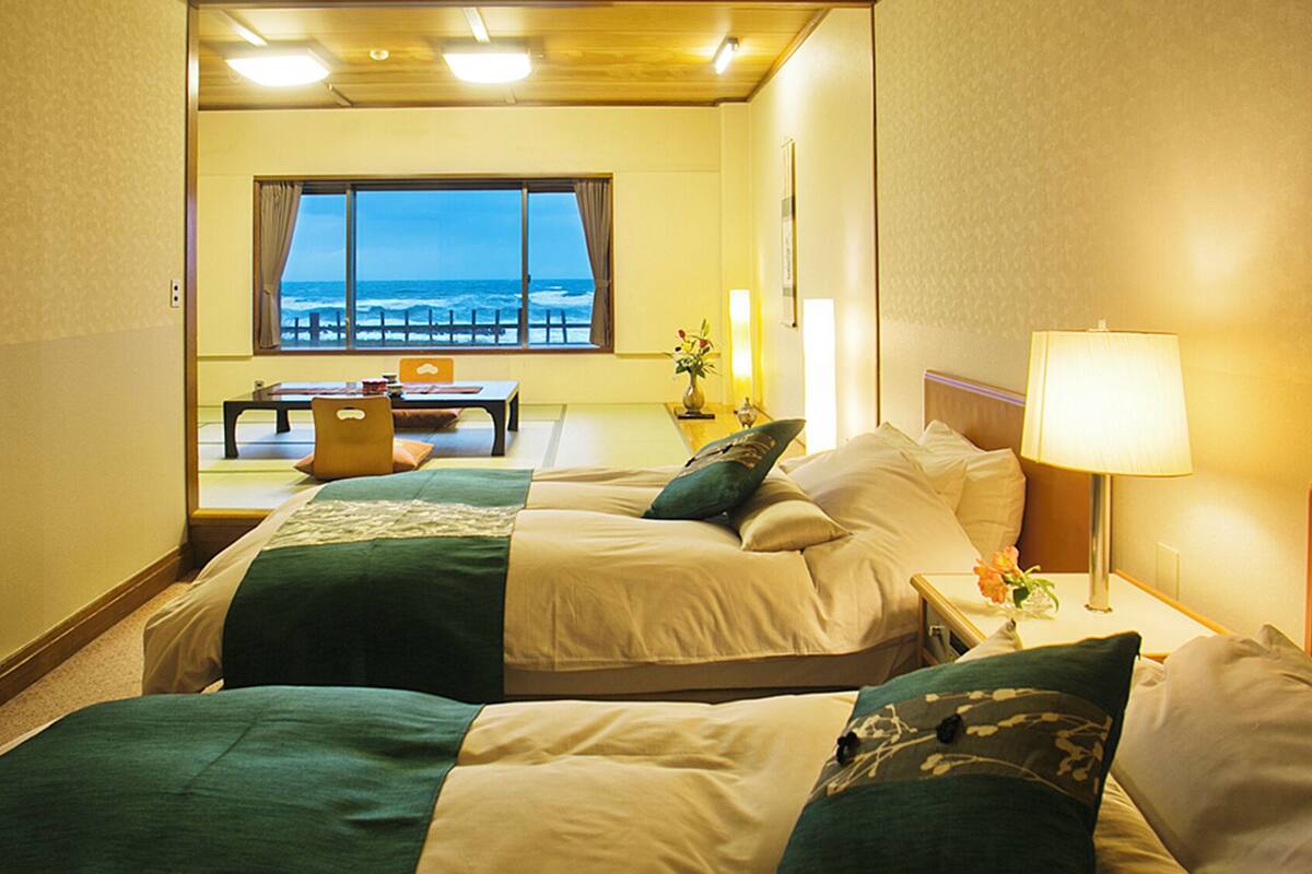 Una habitación de hotel con dos camas, vistas al mar, un comedor y una lámpara.