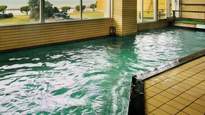 Una amplia piscina cubierta con vistas al mar a través de grandes ventanales.