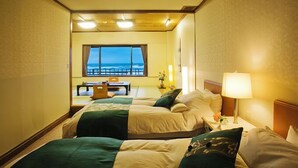 Una habitación de hotel con dos camas, un escritorio y vista al océano.