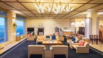 Een ruime hotelbar met een grote zithoek, een open haard en uitzicht op zee.