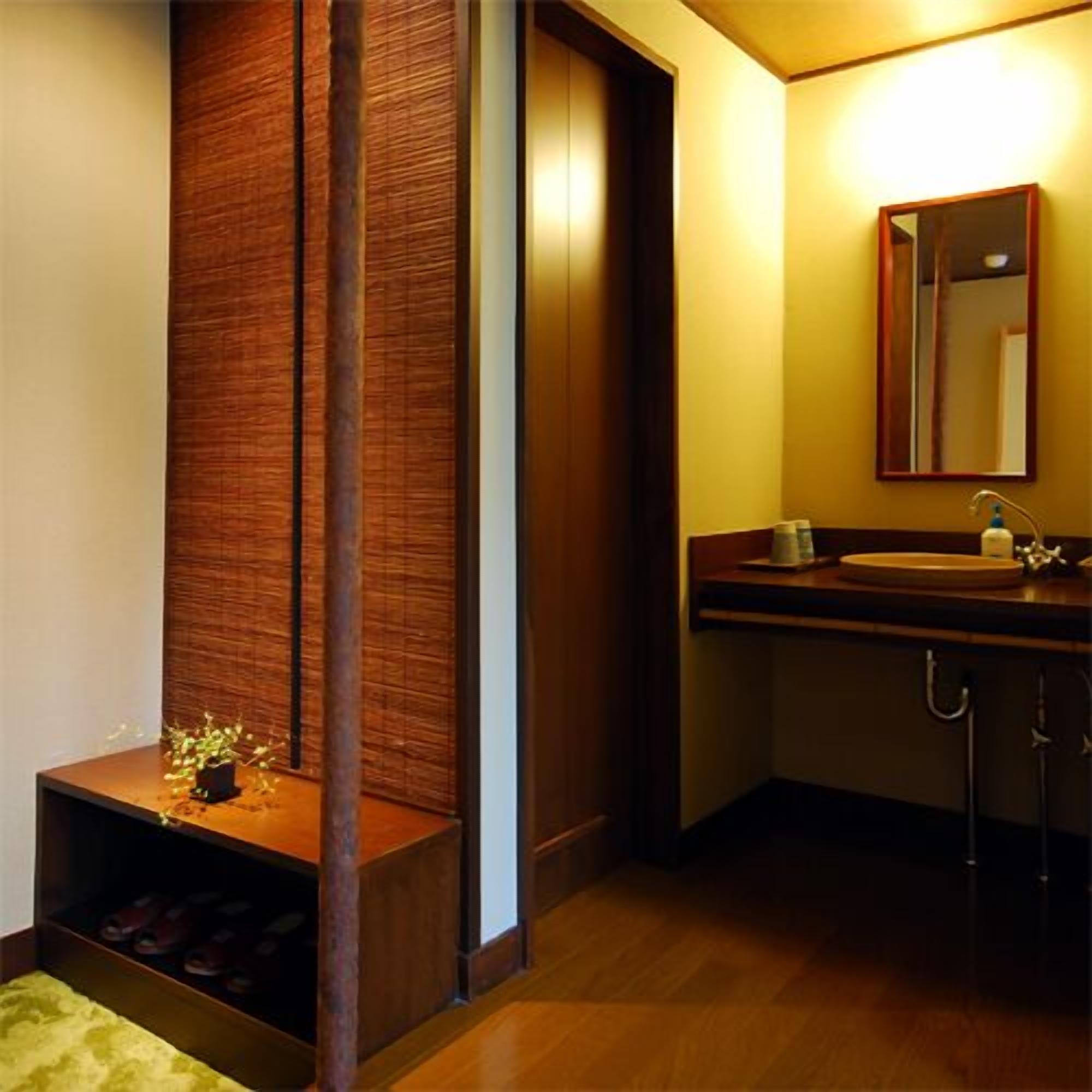 Une salle de bain avec un meuble-lavabo en bois, un miroir, un évier et un porte-chaussures.