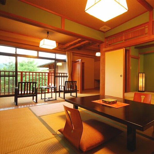 A traditional Japanese room with tatami flooring, a low table, and a view of greenery outside. - Yuden Murakamikan (Shibata)