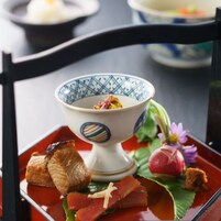 A dining table with a bowl of food, a plate with slices of meat, and a decorative leaf.