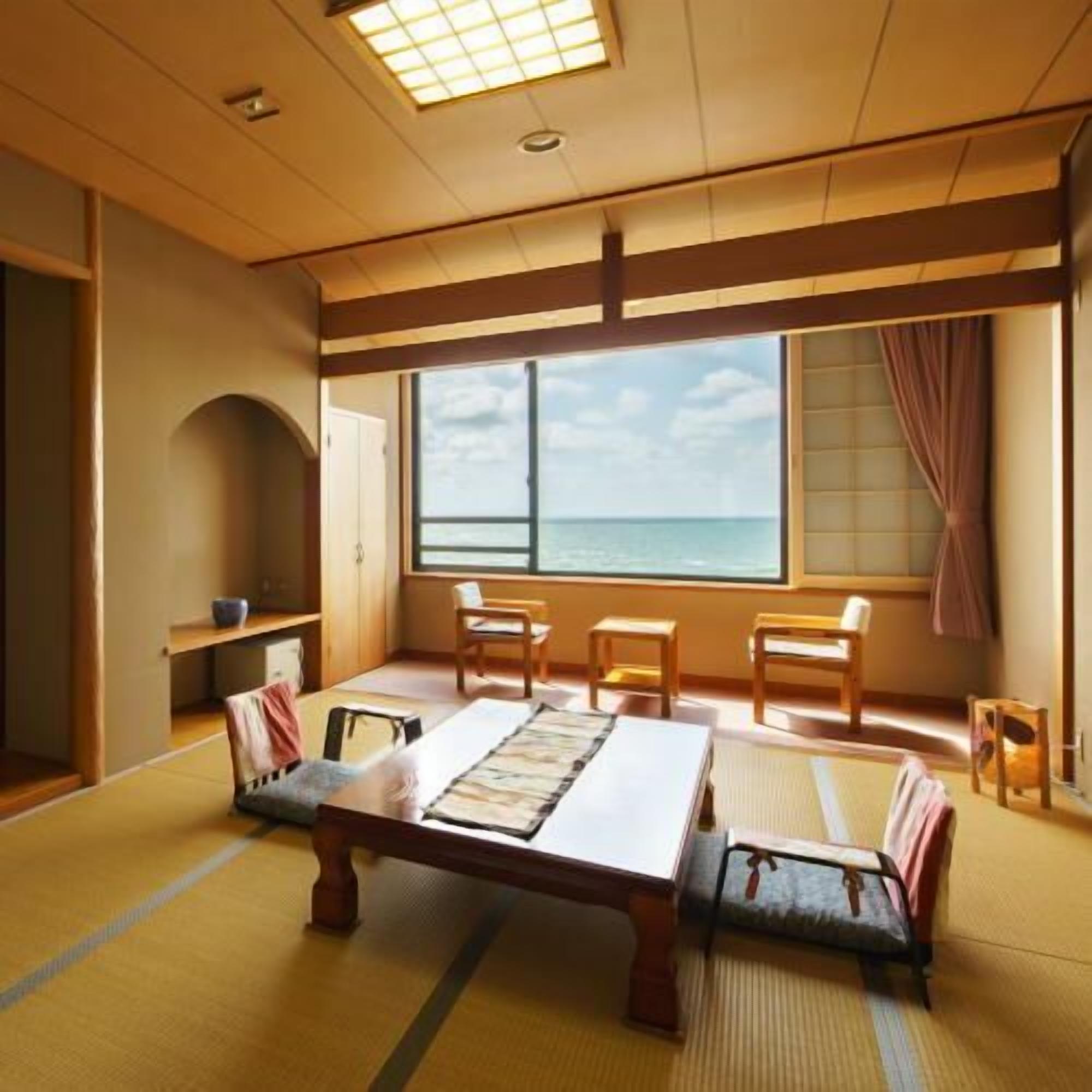 A traditional Japanese room with tatami flooring, a low table, and a view of the sea.