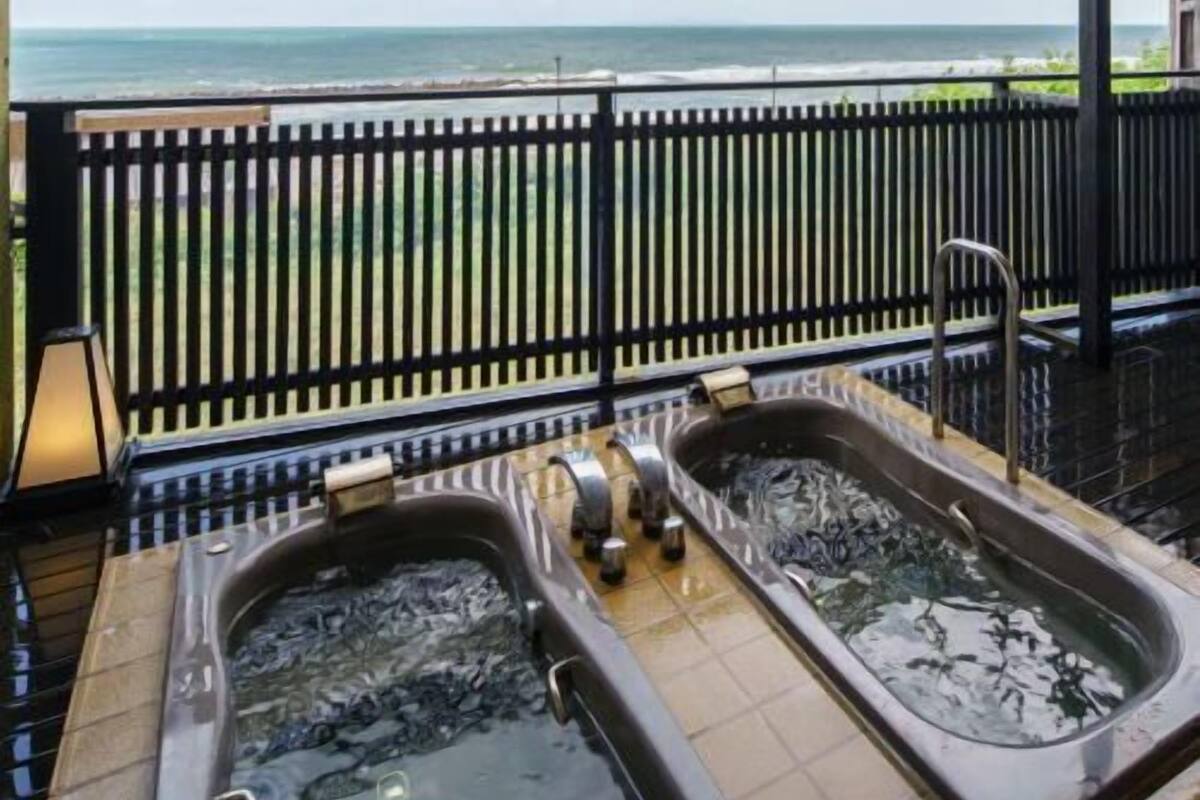 Un balcón con dos jacuzzis, piso de baldosas y vista al océano.