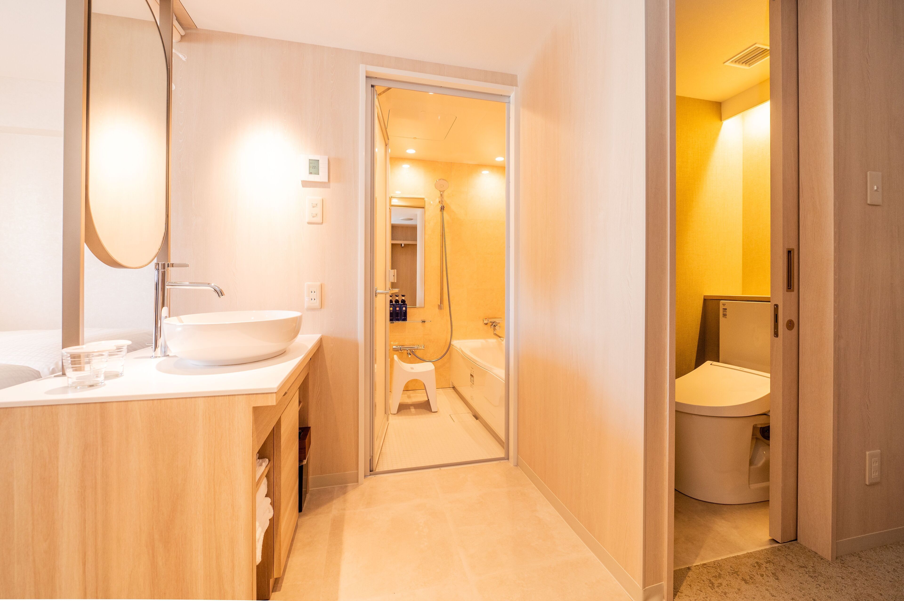 A modern bathroom with a large mirror, a sink, and a toilet.