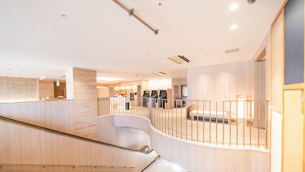 Un interior moderno con una escalera curva, paneles de madera y una zona de estar con barandilla.