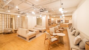 Amplia y luminosa sala de estar con sofás, sillones y una mesa de centro, con un diseño moderno que incluye tuberías a la vista y suelo de madera.