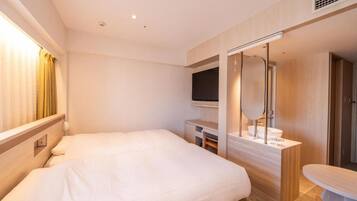 Une chambre d’hôtel moderne dotée d’un grand lit, d’un bureau avec un téléviseur à écran plat, d’une coiffeuse avec un miroir et d’une petite table.