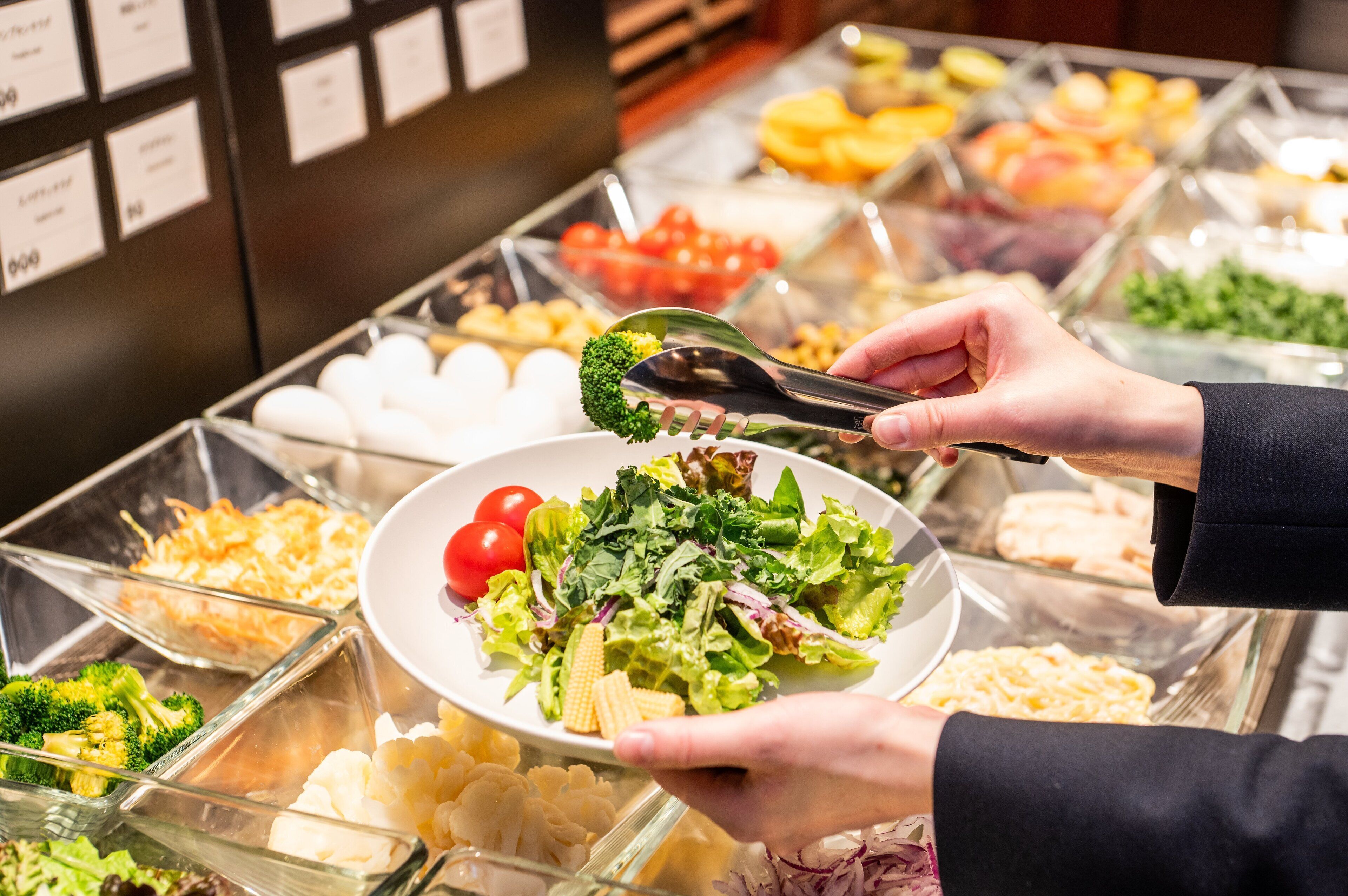 A buffet with various food options, including salads, fruits, and other dishes.