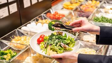 A buffet with various food options, including salads, fruits, and other dishes.