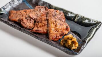 A rectangular plate with grilled meat and a dollop of sauce.