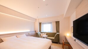 Una habitación de hotel con una cama grande, un sofá, un televisor y una mesita.