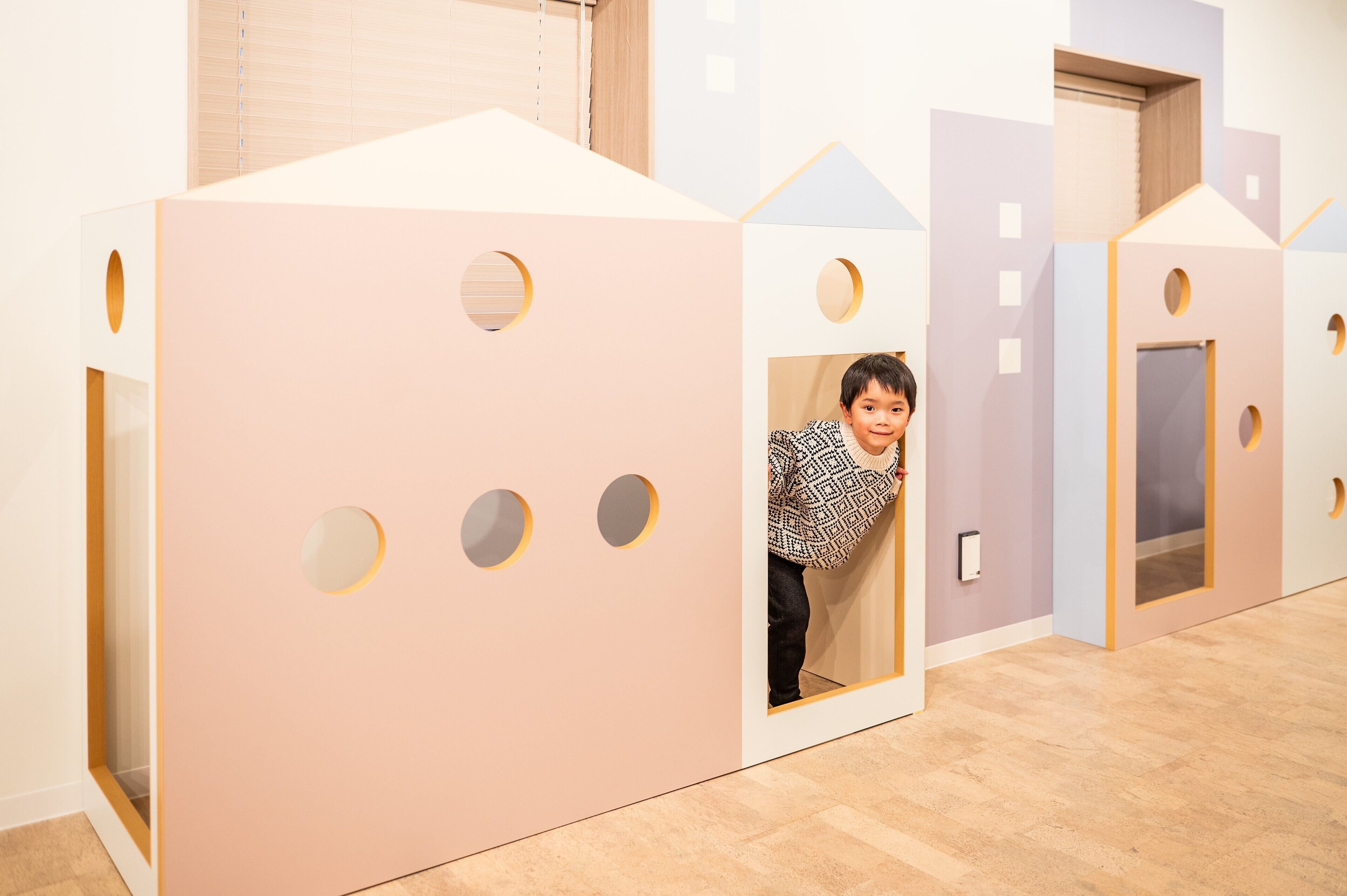 Ein Kind in einer Spielhaus mit Tür und Fenstern.