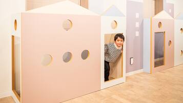 Ein Kind in einer Spielhaus mit Tür und Fenstern.