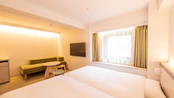 A hotel room with a large bed, a small sofa, a table, and a TV.