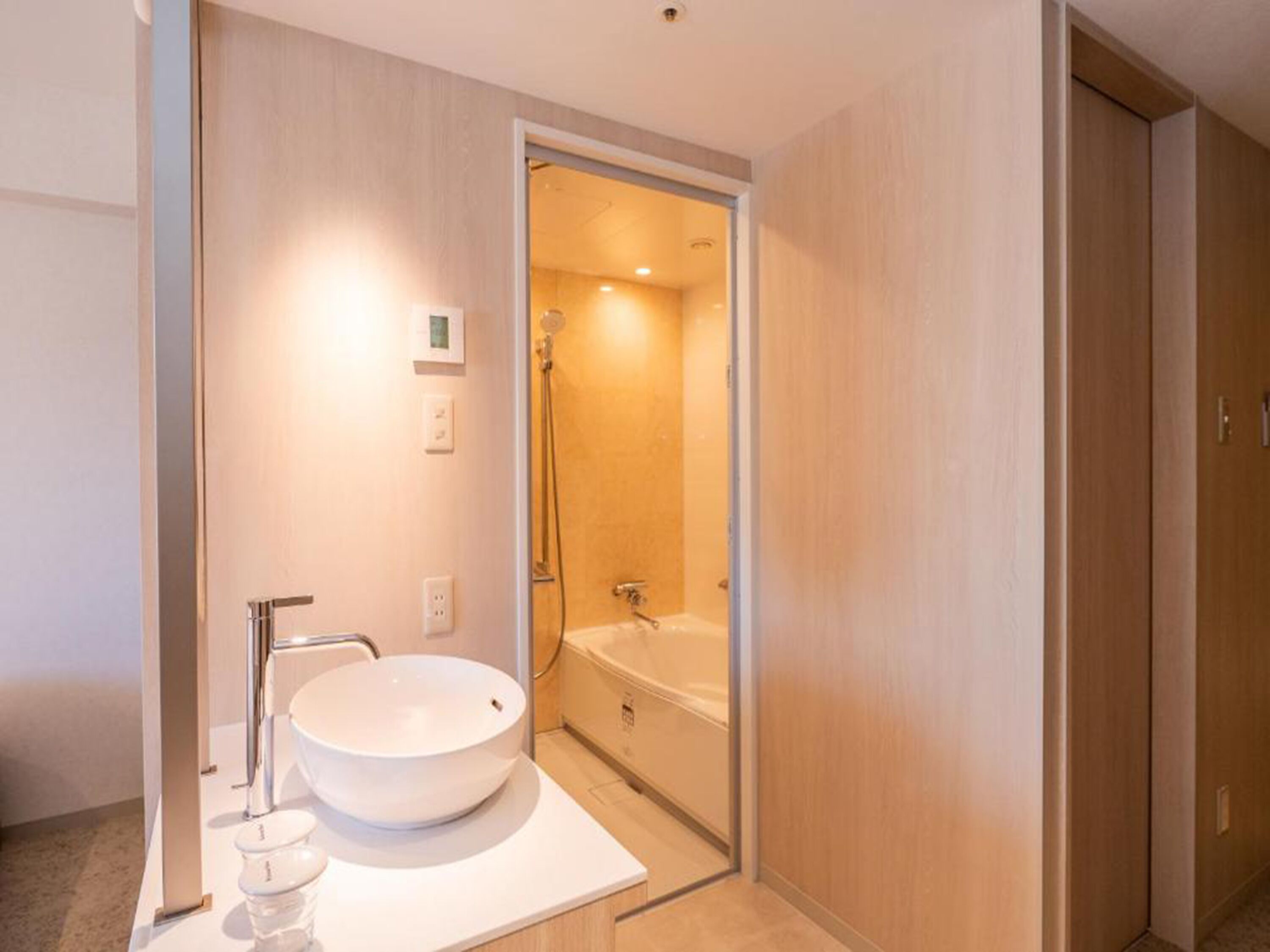 A modern bathroom with a large white sink, a shower, and a toilet.