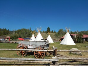 Un sitio histórico con varios tipis blancos y un viejo carruaje.