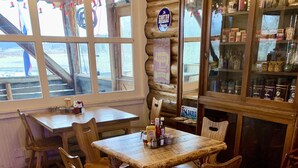 A rustic wooden interior with a large table and chairs, a wooden floor, and a glass display case with various items. - Buffalo Valley Ranch (Moran)