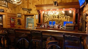 A bar area with a sign reading "The Bronze Boot," wooden walls, and a variety of bottles on the counter. - Buffalo Valley Ranch (Moran)