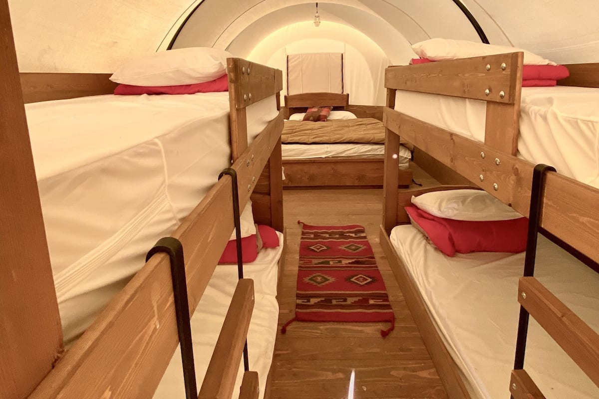 A cozy, circular room with bunk beds, a wooden floor, and a hanging light fixture.