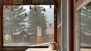 A window view of a rustic cabin with a wooden table and a bucket, decorated with hanging lights and license plates. - Buffalo Valley Ranch (Moran)
