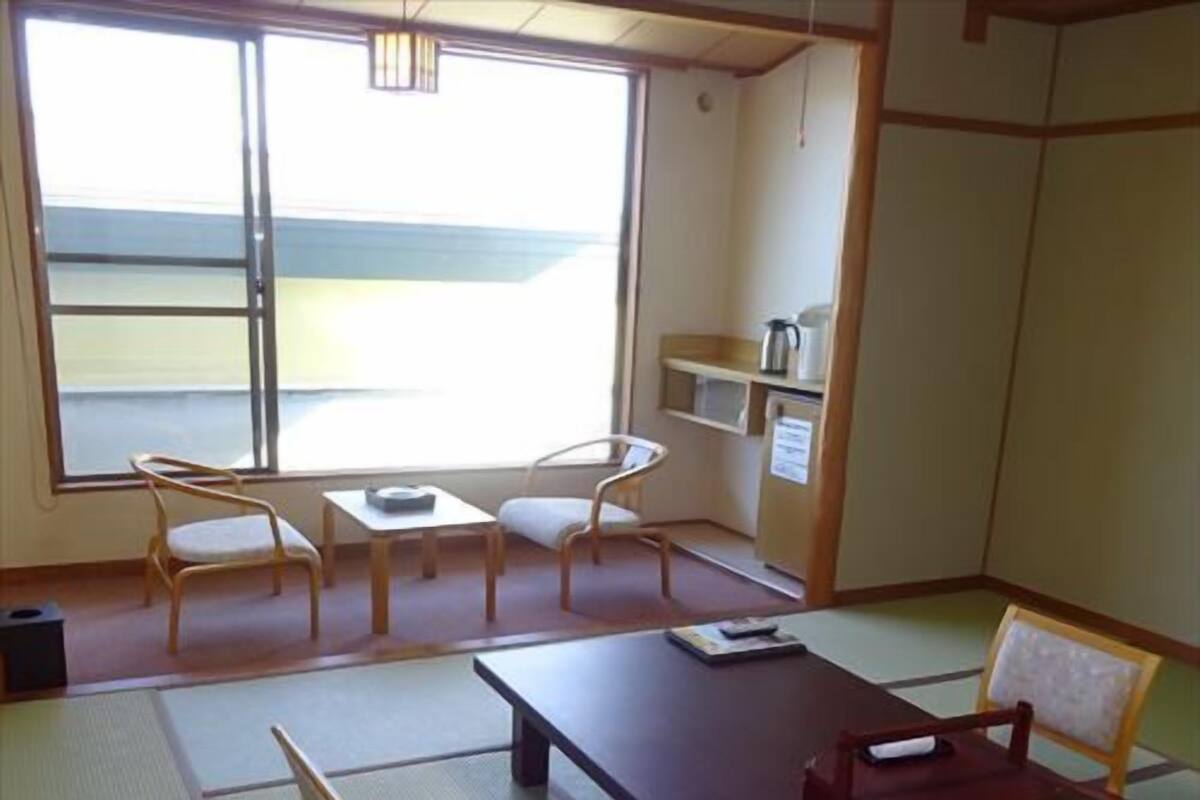 Um quarto japonês tradicional com tatames, uma mesa baixa e cadeiras de madeira.