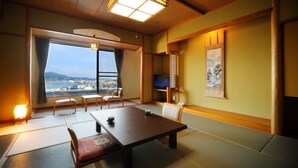 A traditional Japanese room with tatami flooring, a low table, and a sofa. - Sun Marine Kesennuma Hotel Kanyo (Kesennuma)