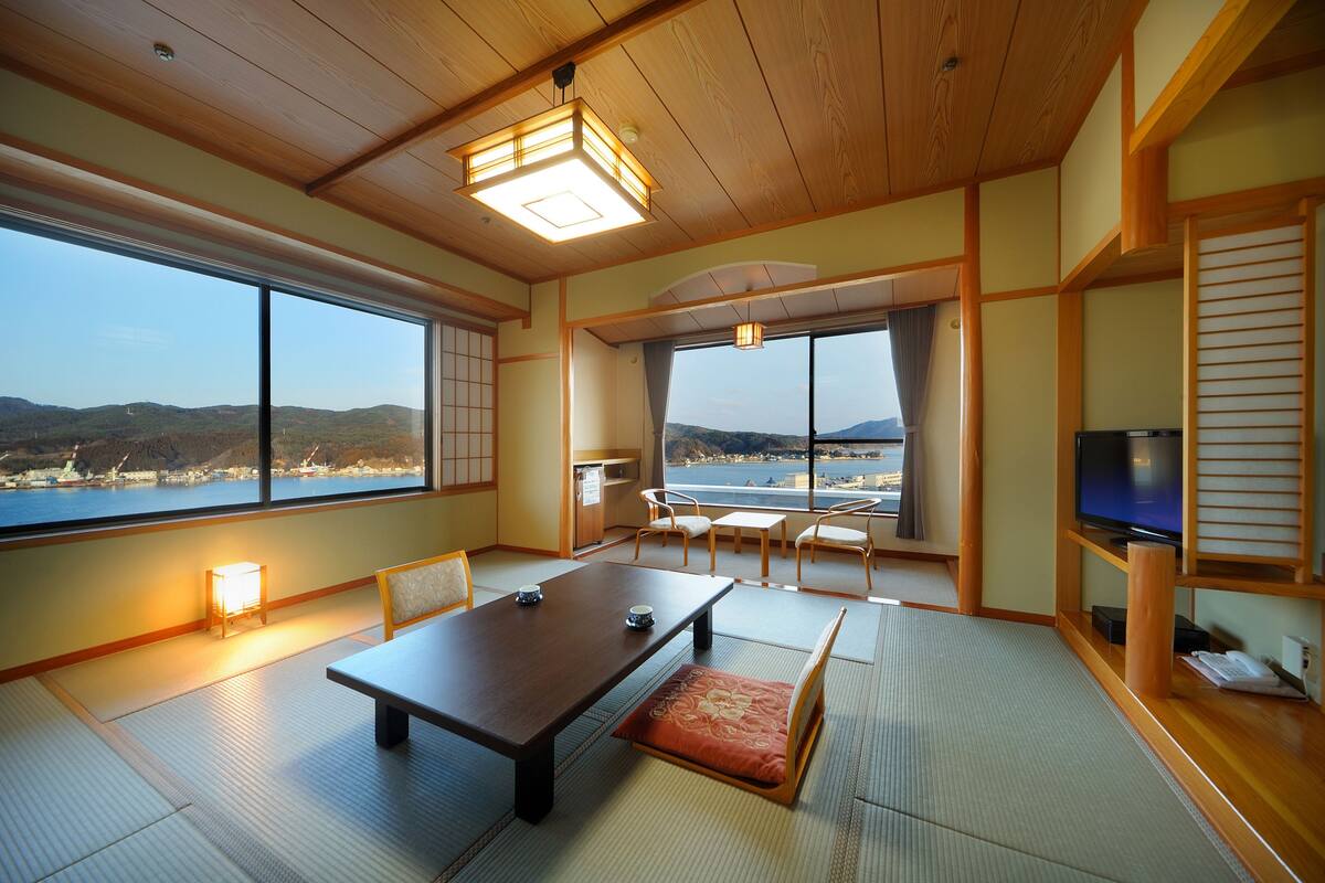 Um quarto japonês tradicional, com tatames, uma mesa baixa e uma televisão.