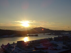 A coastal cityscape during sunset with a body of water, buildings, and a hill in the background. - Sun Marine Kesennuma Hotel Kanyo (Kesennuma)