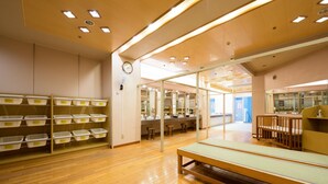 A room with wooden flooring, a bench, and storage units with labeled containers. - Sun Marine Kesennuma Hotel Kanyo (Kesennuma)