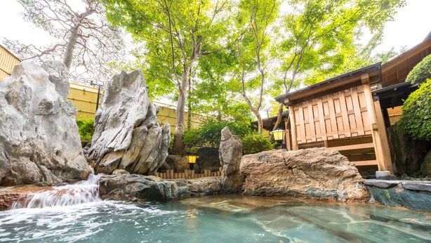 A serene outdoor pool area with clear water, large rocks, and a wooden structure. - Sun Marine Kesennuma Hotel Kanyo (Kesennuma)