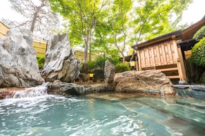 A serene outdoor pool area with clear water, large rocks, and a wooden structure. - Sun Marine Kesennuma Hotel Kanyo (Kesennuma)