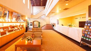 A hotel lobby with a reception desk, seating area, and a display of books and magazines. - Hotel Pearl City Kesennuma (Kesennuma)