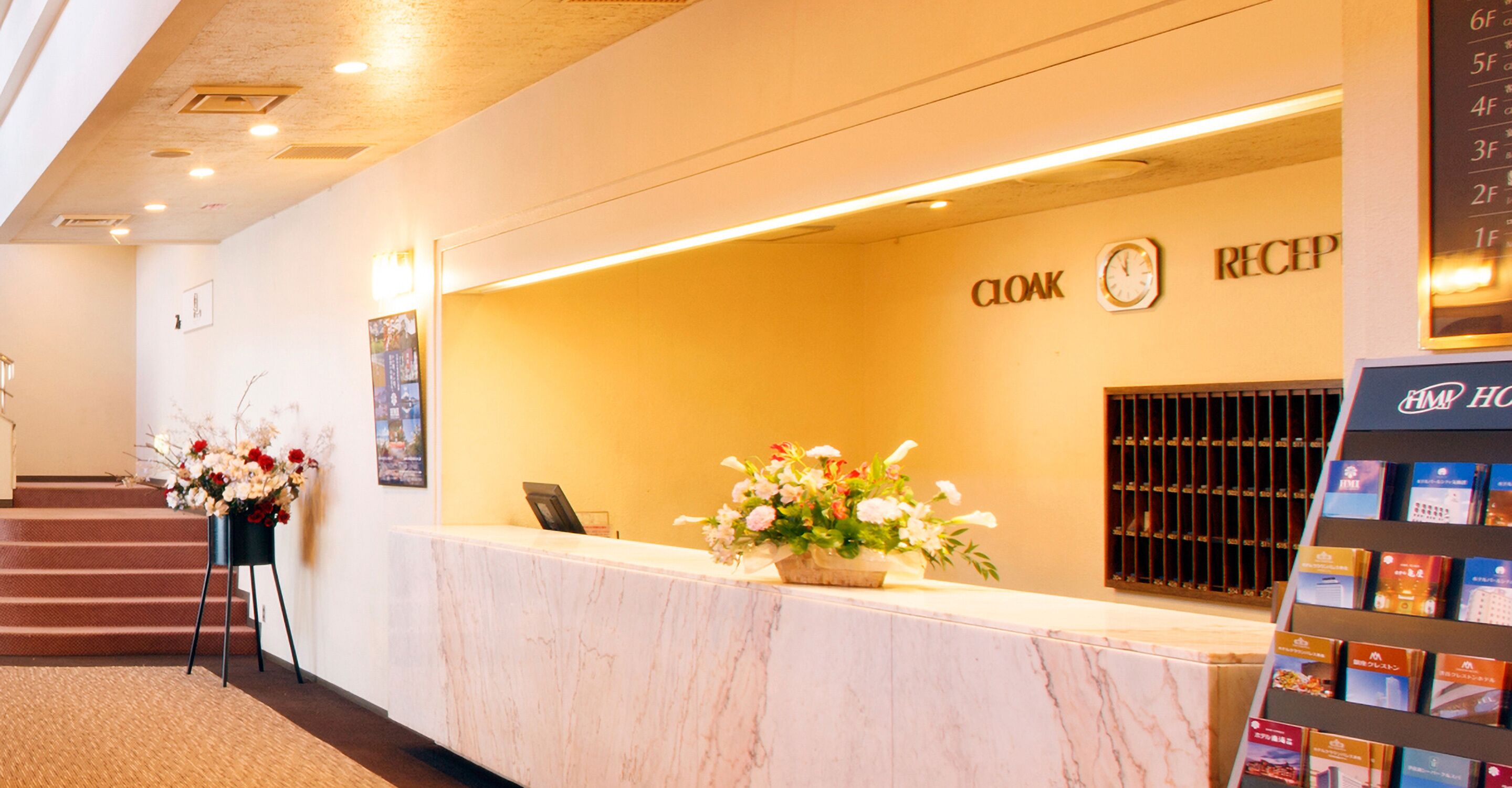 Ein Hotel-Empfangsbereich mit Marmorzauber, einer Uhr und einem Empfangstresen.