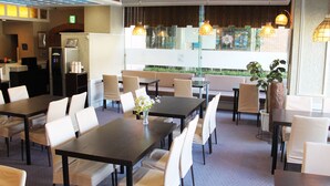 A restaurant with multiple dining tables and chairs, a refrigerator, and hanging lights. - Hotel Pearl City Kesennuma (Kesennuma)