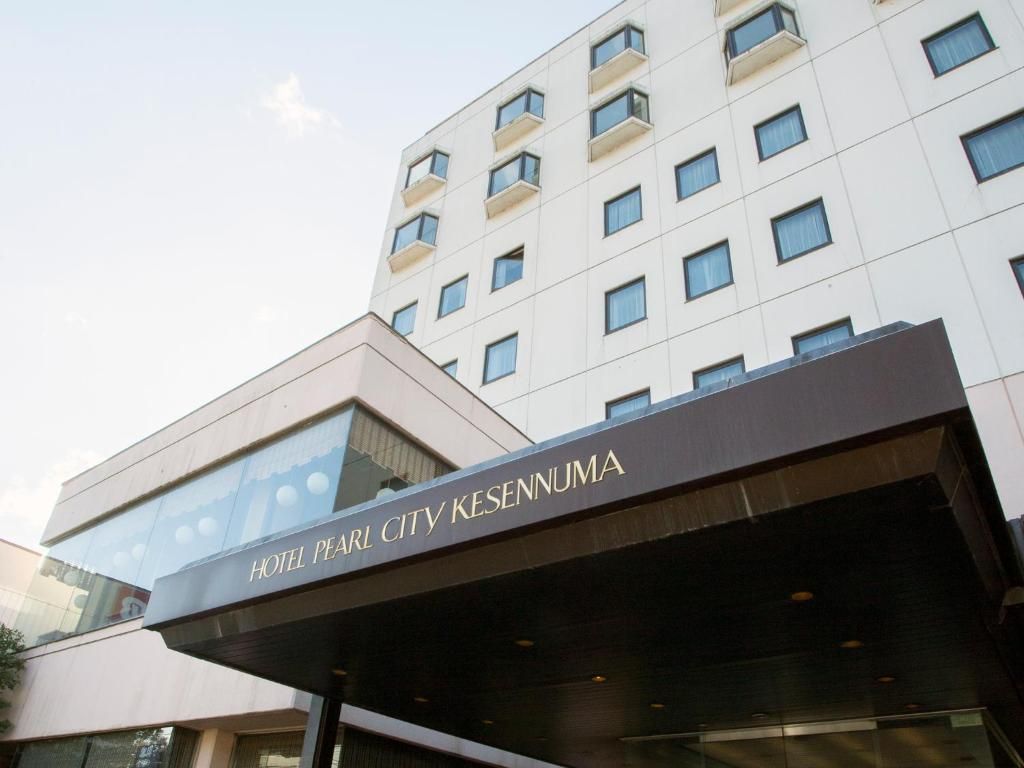 Un hotel amb una façana moderna, una entrada destacada i un rètol que indica el nom 'HOTEL PEARL CITY KESENNUMA'.