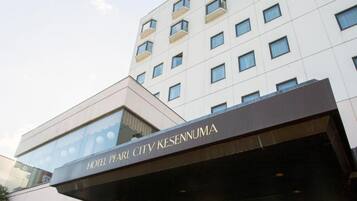 Un hotel amb una façana moderna, una entrada destacada i un rètol que indica el nom 'HOTEL PEARL CITY KESENNUMA'.