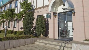 A building entrance with a glass door, steps leading up to it, and a bike rack outside. - Hotel Folkloro Takahata Jr-east Hotels (Takahata)