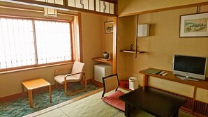 A traditional Japanese-style room with tatami flooring, a low table, a sofa, a television, and a small refrigerator. - Wakaba-ryokan (Sakata)