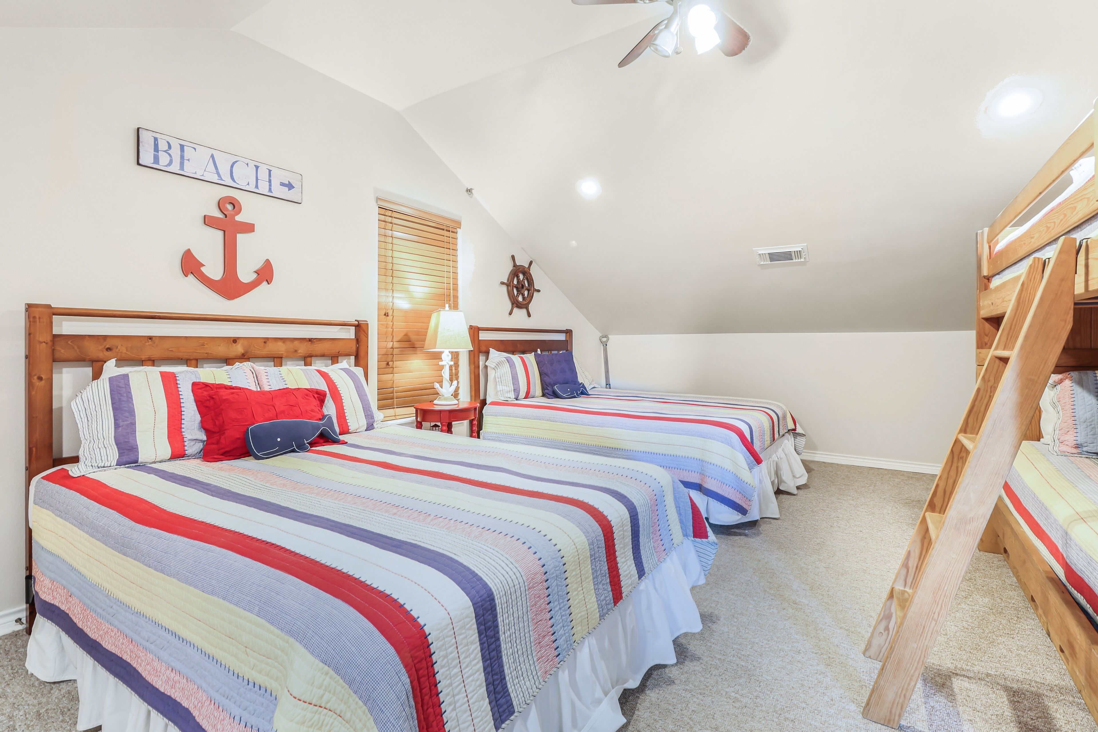 A bedroom with two beds, a bunk bed, and nautical-themed decor.