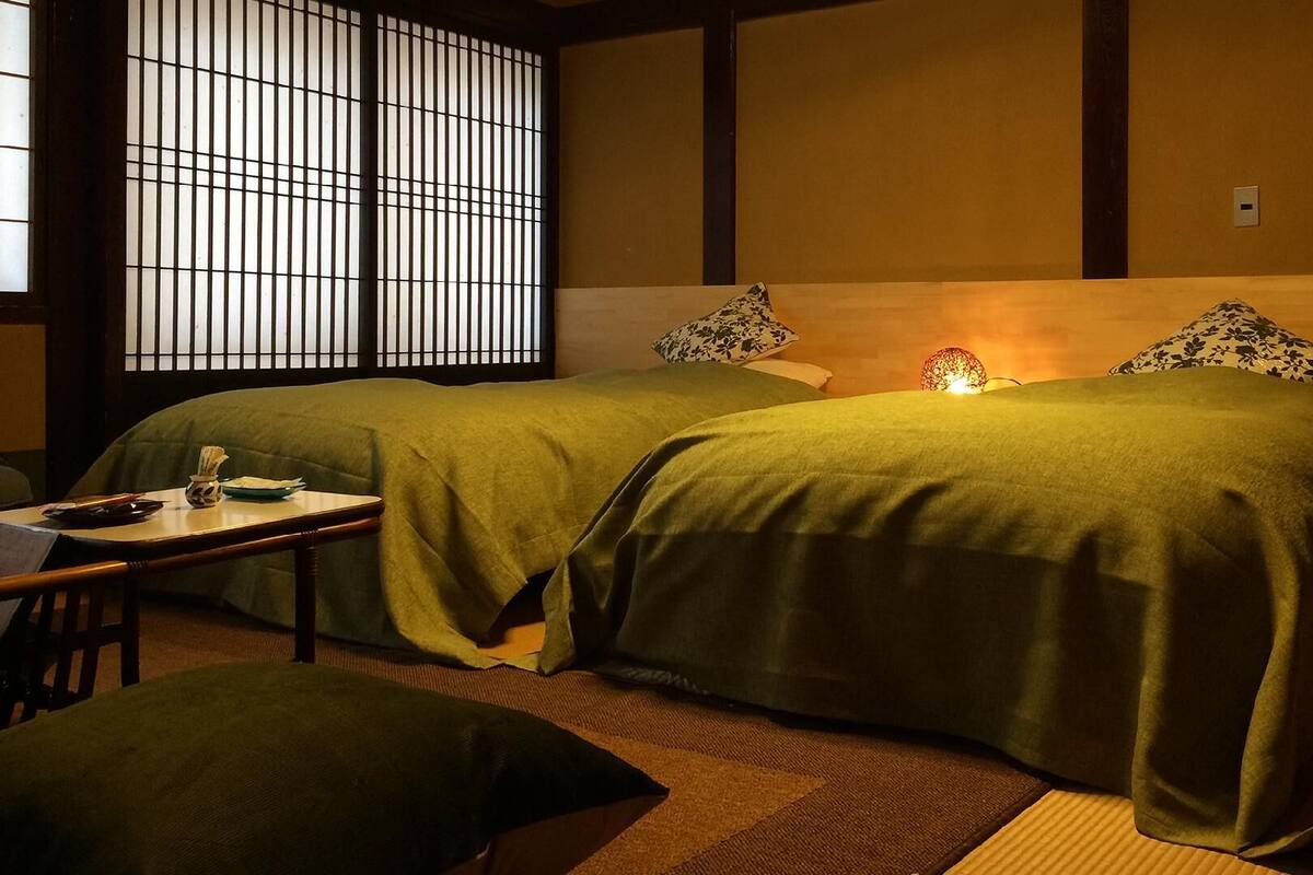 A traditional Japanese-style room with two beds, a small table, and a tatami mat floor.