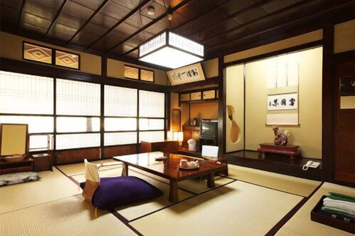 A traditional Japanese room with tatami flooring, a low table, a cushion, and sliding doors.