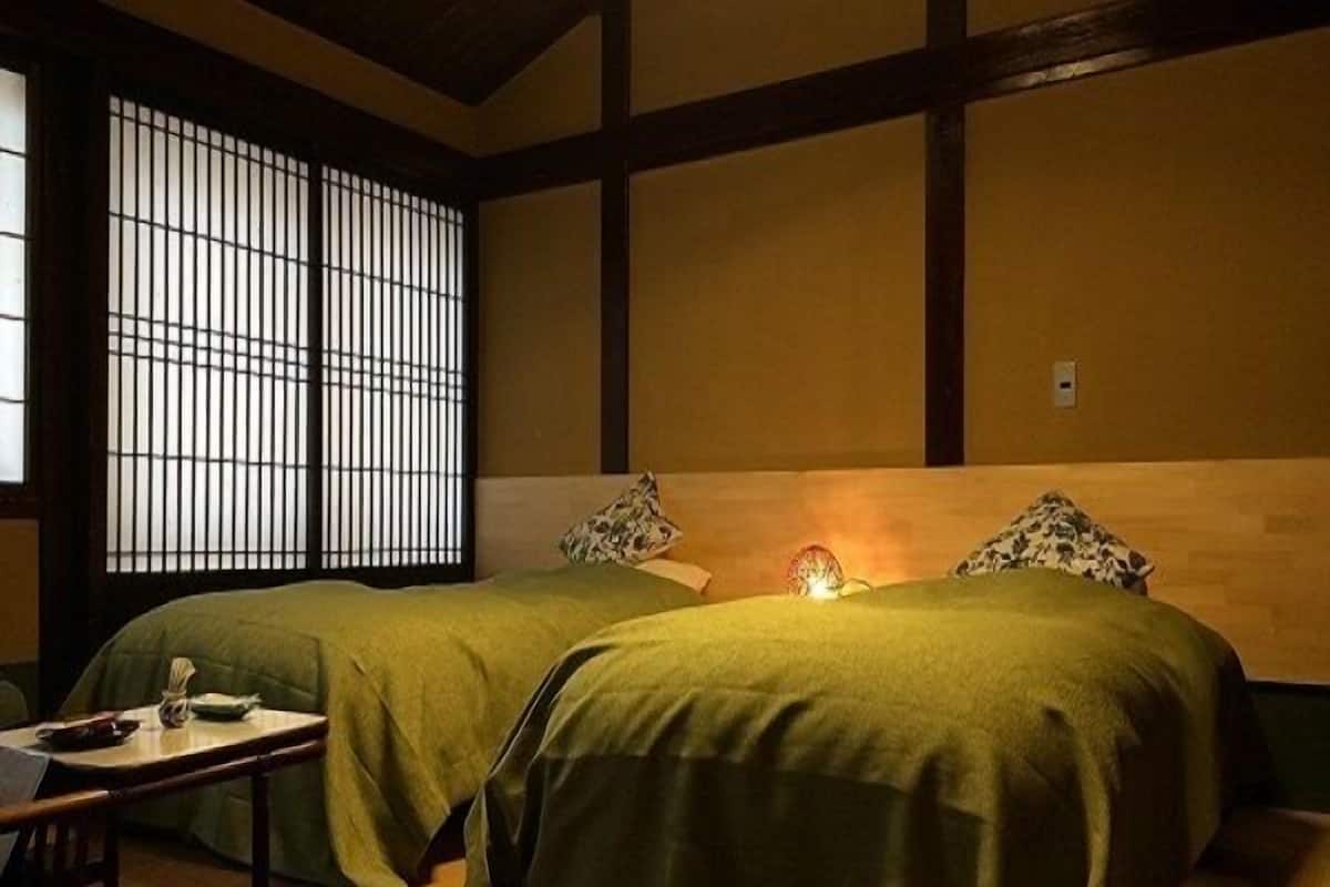 A traditional Japanese-style room with two beds, a small table, and a futon.