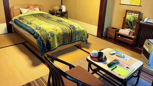 A hotel room with a bed, bedside table, chair, desk, and a mirror. - Nishiya (Yonezawa)