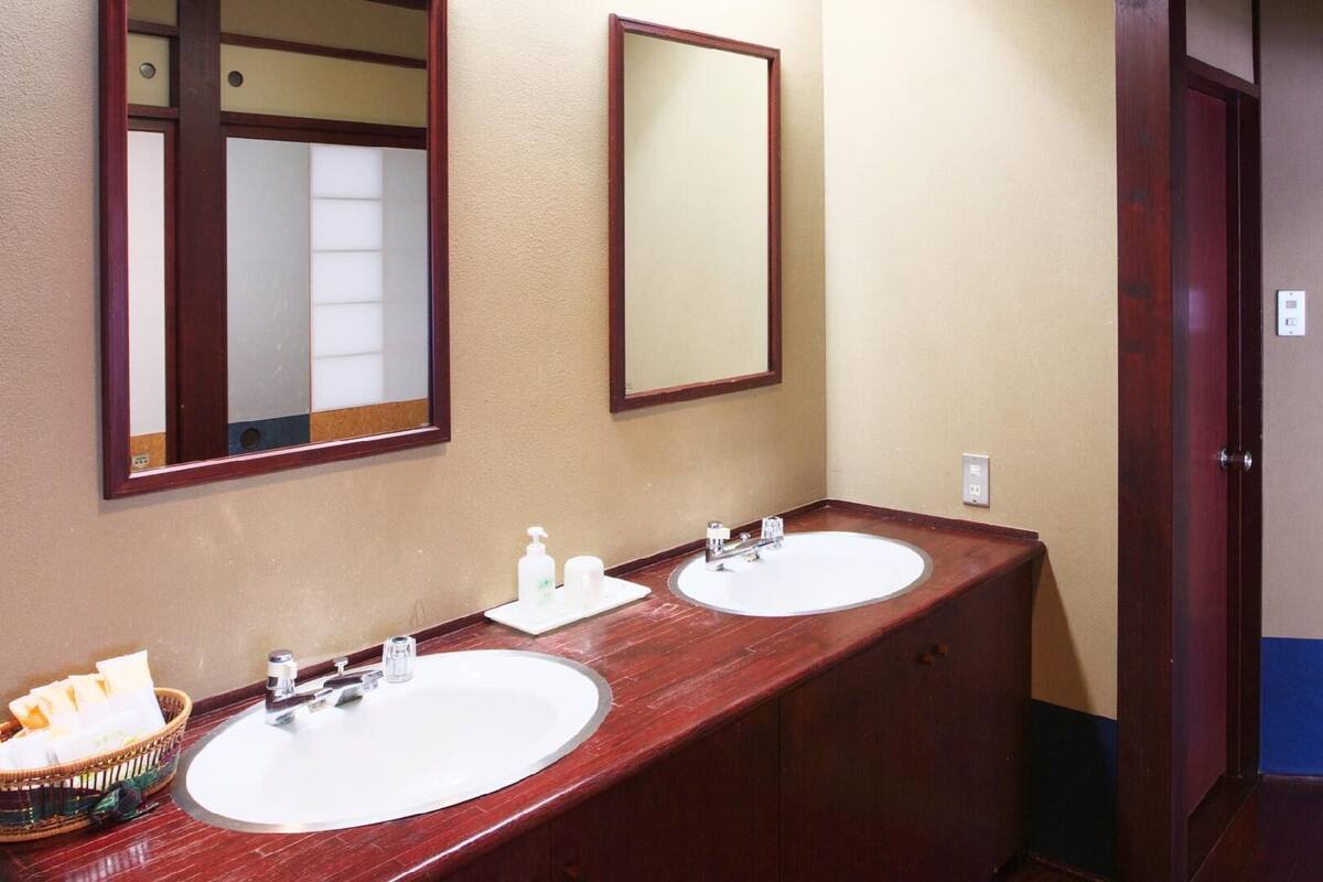 A bathroom with two sinks, a mirror, and a basket of toiletries.