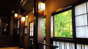 A hallway with wooden doors and windows, a staircase, and a railing. - Nishiya (Yonezawa)